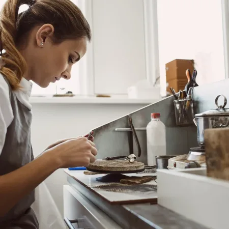 secret-technology-side-view-of-young-female-jeweler-working-on-a-new-silver-ring-at-her-workbench