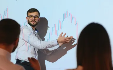 trading-teaching-male-leader-talking-to-employees-showing-the-plan-on-the-projector-in-office